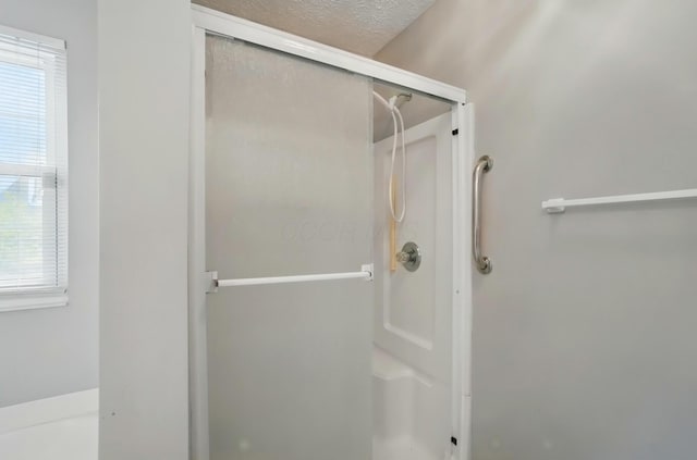 bathroom with a shower stall and a textured ceiling