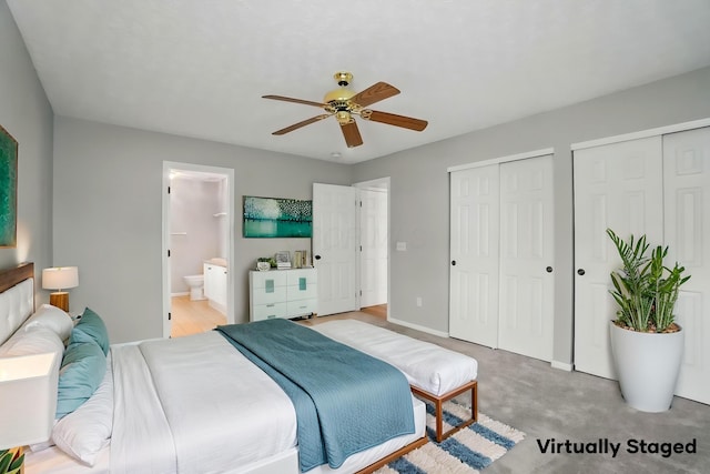 bedroom featuring a ceiling fan, multiple closets, light carpet, baseboards, and ensuite bath