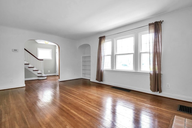 461 E N Broadway St, Columbus, OH 43214 - unfurnished living room with arched walkways, hardwood / wood-style flooring, baseboards, and stairs