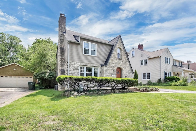 461 E N Broadway St, Columbus, OH 43214 - tudor house featuring a garage, stone siding, a front lawn, and an outdoor structure