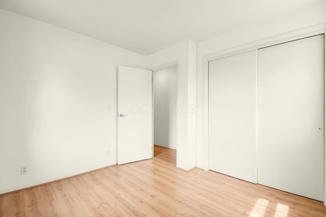 unfurnished bedroom featuring a closet and light wood-style flooring