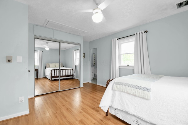 bedroom featuring baseboards, visible vents, light wood finished floors, and attic access