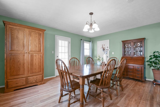 dining space featuring an inviting chandelier, baseboards, and light wood-type flooring
