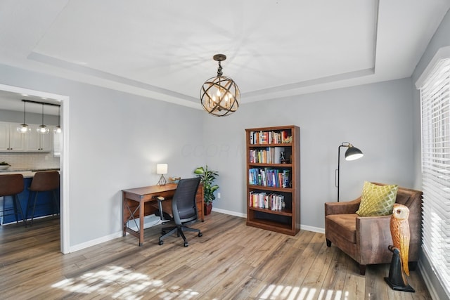 home office with baseboards, wood finished floors, a chandelier, and a raised ceiling