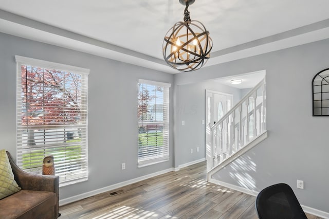 interior space with stairs, wood finished floors, an inviting chandelier, baseboards, and visible vents