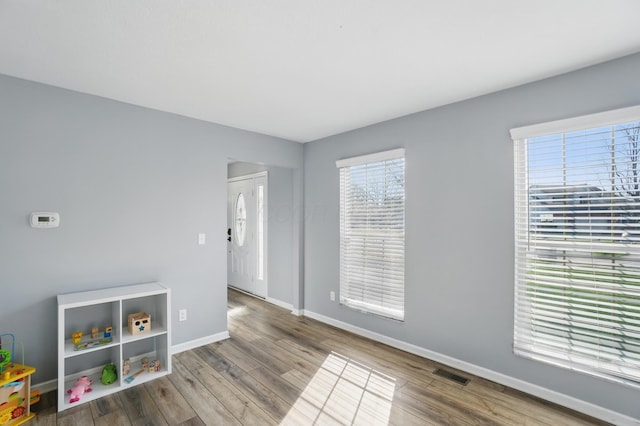 interior space with baseboards, wood finished floors, and visible vents