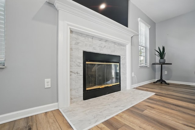 interior details with baseboards, wood finished floors, a tile fireplace, and visible vents