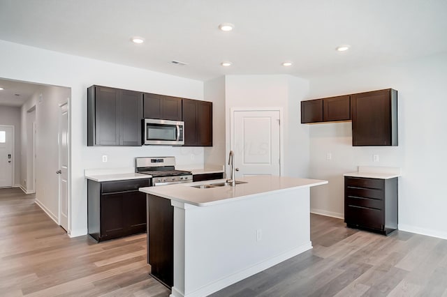 kitchen with light countertops, light wood-style flooring, stainless steel appliances, and a sink