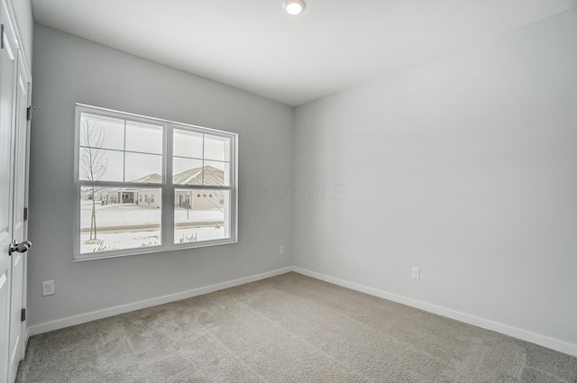 carpeted empty room featuring baseboards