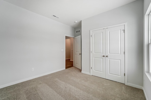 unfurnished bedroom featuring baseboards, a closet, visible vents, and carpet