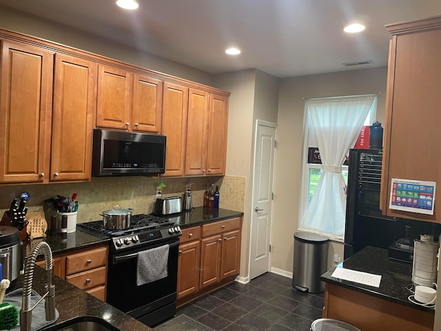 kitchen featuring brown cabinets, dark stone countertops, tasteful backsplash, visible vents, and range with gas cooktop