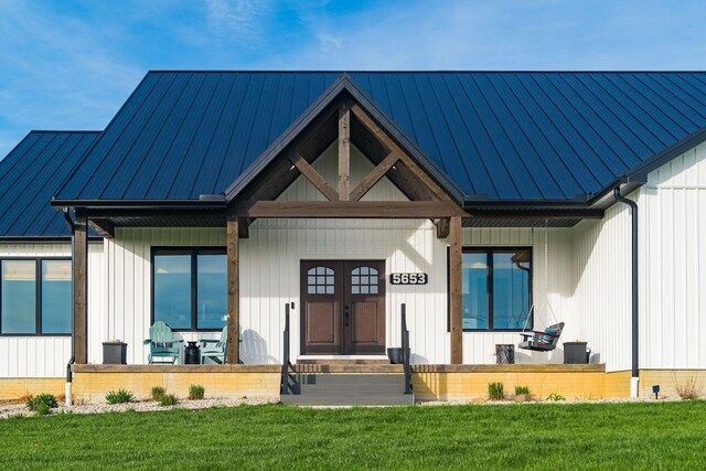 view of front of property featuring a standing seam roof, covered porch, metal roof, and a front yard