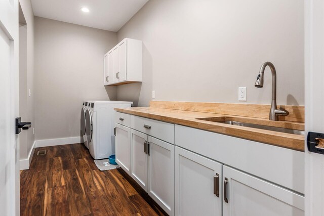 clothes washing area featuring a sink, separate washer and dryer, cabinet space, dark wood finished floors, and baseboards