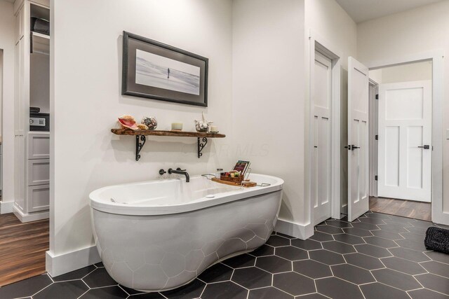 bathroom with a soaking tub and baseboards