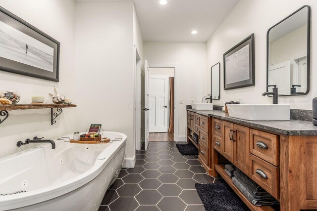 full bathroom featuring recessed lighting, double vanity, a tub with jets, and a sink