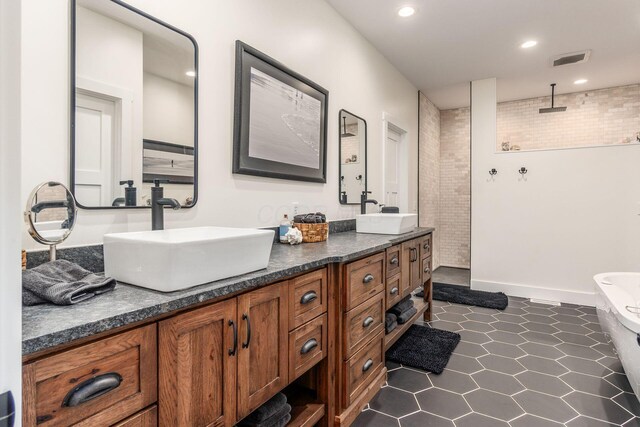 bathroom with walk in shower, visible vents, a sink, and double vanity