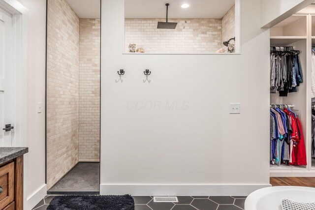 full bathroom with a walk in closet, tile patterned floors, vanity, and a walk in shower