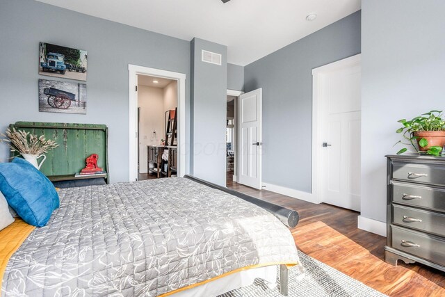 bedroom featuring baseboards, wood finished floors, and visible vents