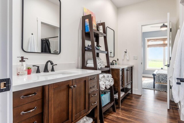 ensuite bathroom featuring baseboards, wood finished floors, ensuite bath, and vanity