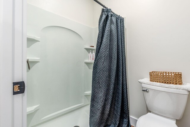 full bathroom featuring a shower stall and toilet