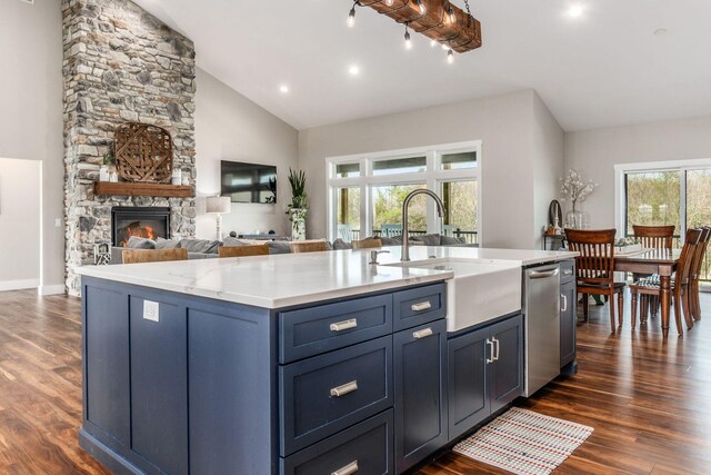 kitchen with dark wood-style floors, stainless steel dishwasher, a sink, and a kitchen island with sink