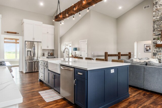kitchen featuring high vaulted ceiling, a sink, stainless steel appliances, white cabinets, and visible vents