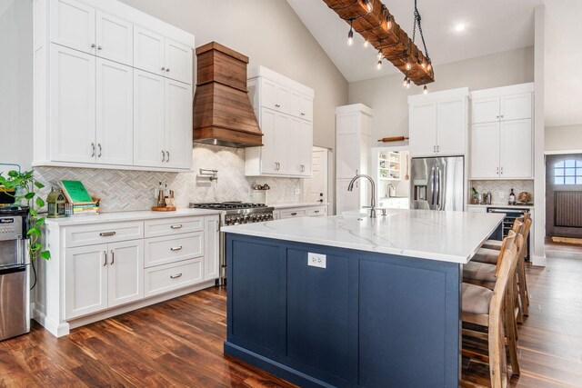 kitchen with a sink, vaulted ceiling, decorative backsplash, appliances with stainless steel finishes, and premium range hood