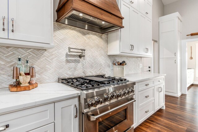 kitchen featuring backsplash, range with two ovens, custom exhaust hood, and white cabinetry