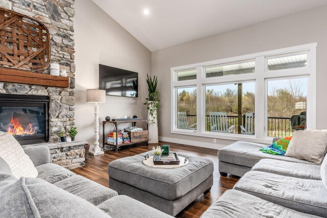 living room with a stone fireplace, wood finished floors, and high vaulted ceiling