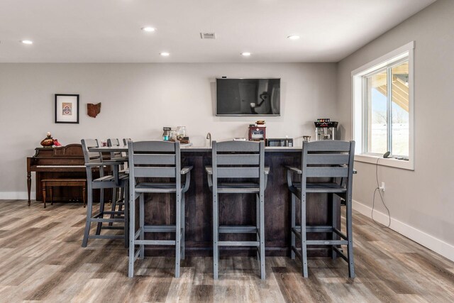 bar featuring wet bar, baseboards, visible vents, recessed lighting, and wood finished floors