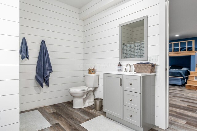 bathroom featuring wood walls, wood finished floors, vanity, a shower with curtain, and toilet