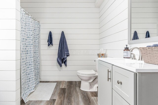 bathroom with vanity, wood finished floors, and wooden walls