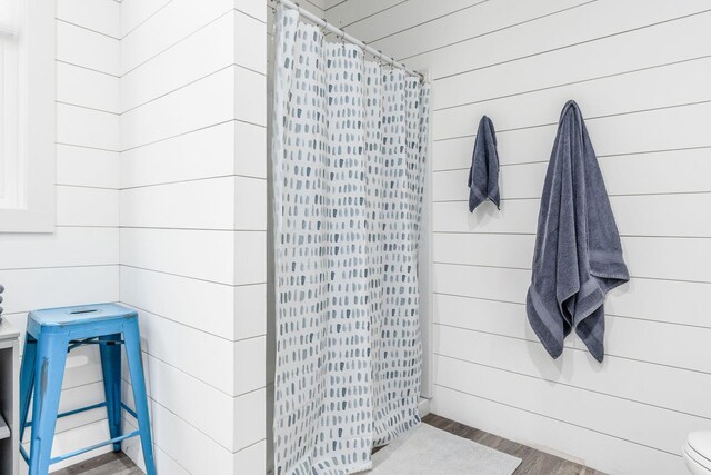 full bath with wood walls, wood finished floors, and a shower with shower curtain