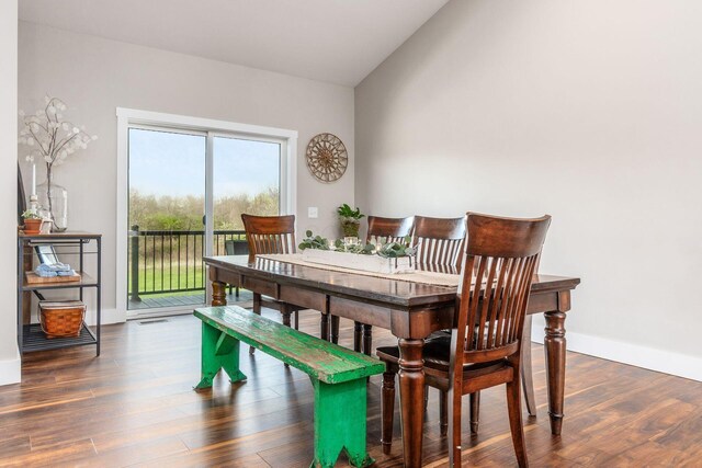 dining area with vaulted ceiling, wood finished floors, and baseboards