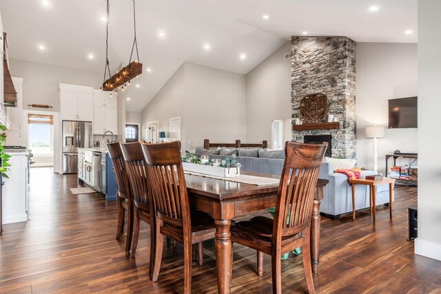 dining space featuring a fireplace, high vaulted ceiling, recessed lighting, and dark wood finished floors
