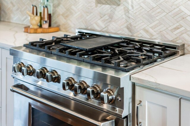 room details with high end range, light stone counters, and tasteful backsplash