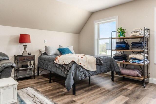 bedroom with vaulted ceiling and wood finished floors