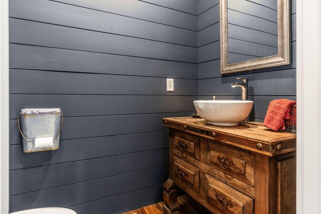 bathroom with vanity, wood finished floors, and wooden walls