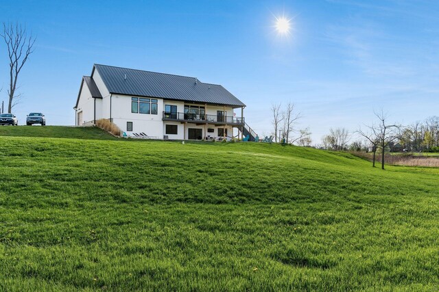 back of property featuring a deck, a yard, and metal roof