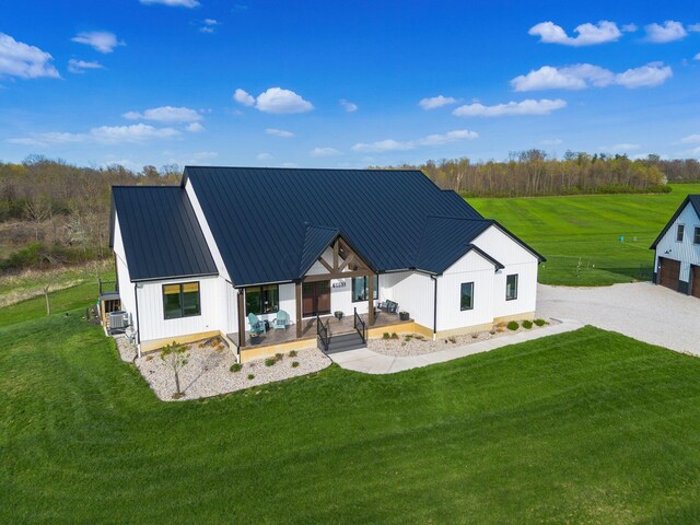 back of property featuring board and batten siding, covered porch, a lawn, and metal roof