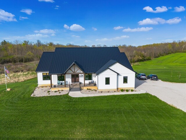 modern inspired farmhouse featuring a standing seam roof, a front lawn, a porch, metal roof, and board and batten siding