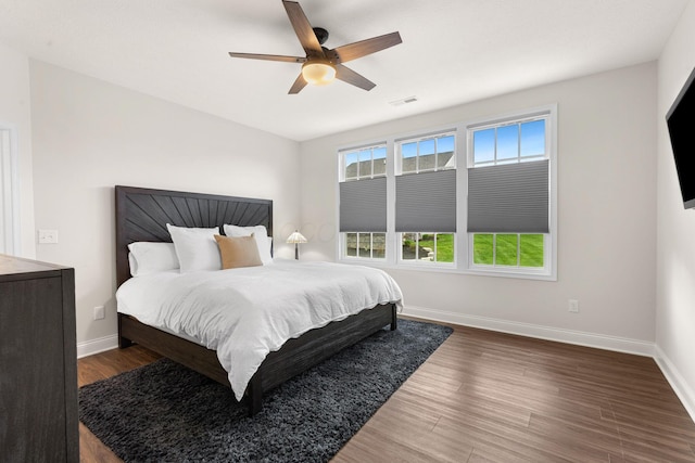 bedroom featuring visible vents, baseboards, ceiling fan, and wood finished floors