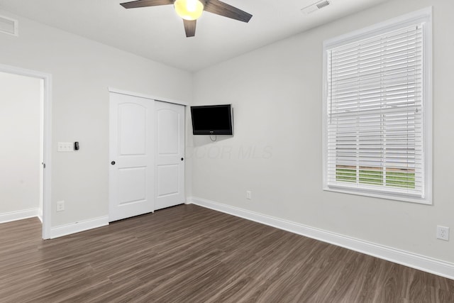 unfurnished bedroom featuring ceiling fan, visible vents, baseboards, a closet, and dark wood-style floors