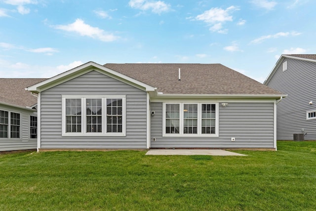 rear view of property with roof with shingles, central AC, and a yard