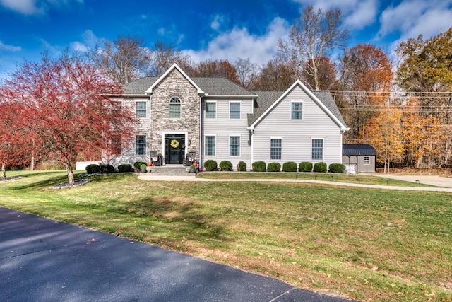 779 Millstone Ln, Mount Vernon, OH 43050 - colonial house featuring a shingled roof, a storage shed, an outdoor structure, stone siding, and a front yard