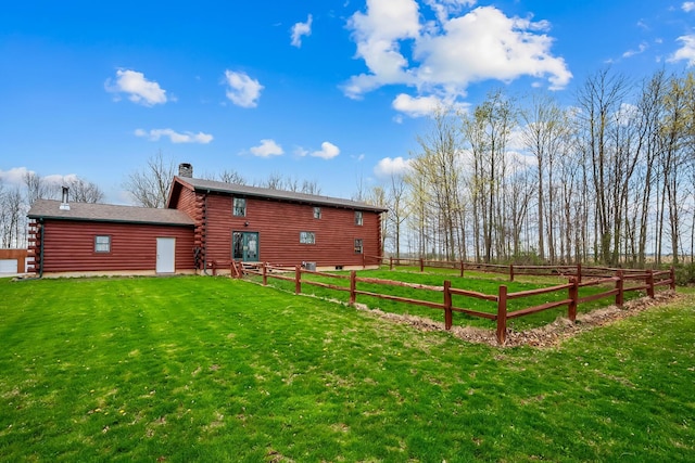 back of property with a chimney, log exterior, fence, and a yard