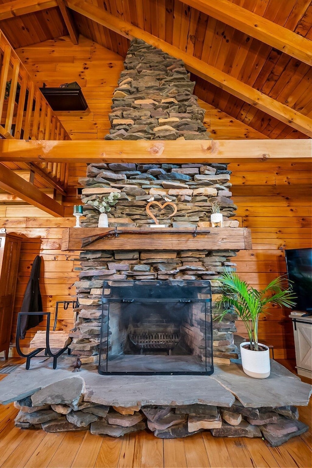 details featuring wood ceiling, wooden walls, a stone fireplace, and beamed ceiling