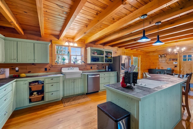 kitchen with wood walls, stainless steel appliances, open shelves, light wood-style floors, and green cabinets