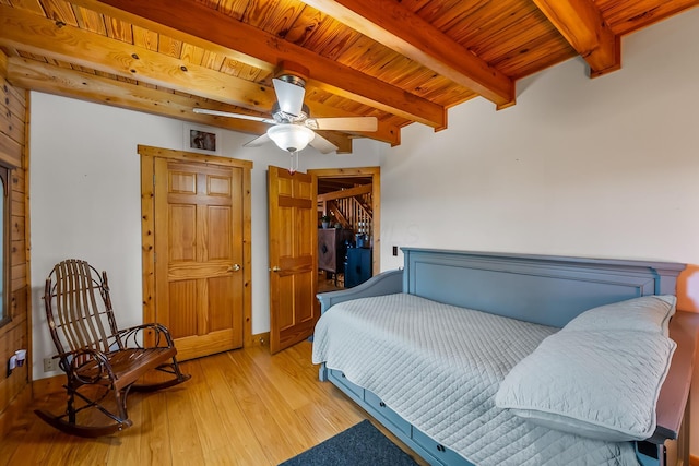bedroom featuring beam ceiling, baseboards, ceiling fan, wood ceiling, and wood-type flooring