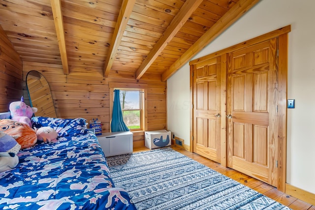 bedroom with light wood-type flooring, vaulted ceiling with beams, wood walls, and wooden ceiling